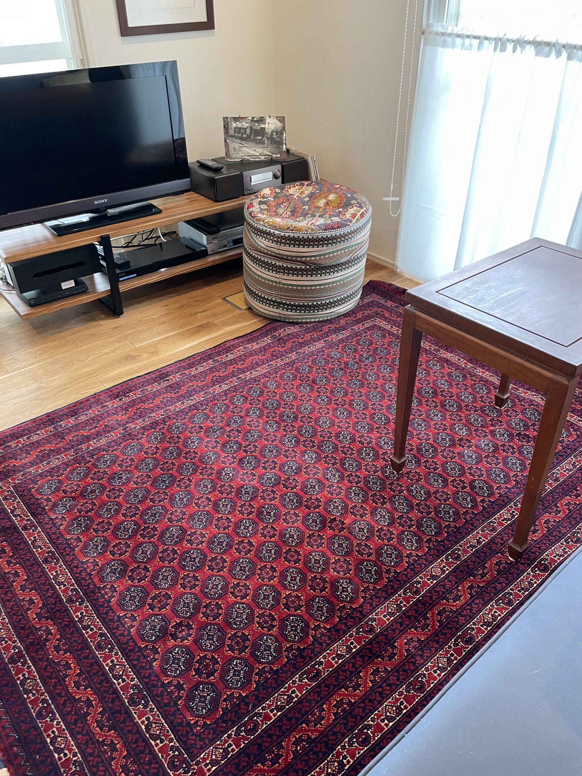 お客様宅に納品されたアフガン絨毯と、窓から差し込む自然光の柔らかな風景